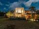 A-frame home with a wall of glass, porch, and pergola, showcasing the property's unique architectural design at dusk at 1627 Bayshore Dr, Englewood, FL 34223