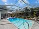 Screened in pool with chairs and patio, surrounded by lush landscaping at 1627 Bayshore Dr, Englewood, FL 34223