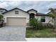 Charming single Gathering home featuring a two-car garage, brick paved driveway, and tropical landscaping at 19715 Tortuga Cay Dr, Venice, FL 34293