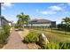 Backyard featuring a brick walkway, lush green lawn, decorative rock, and privacy fence at 20078 Elegante Ct, Venice, FL 34293