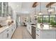 A modern white kitchen featuring granite countertops, stainless steel appliances, and a stylish island with wooden beam design at 20078 Elegante Ct, Venice, FL 34293