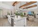 White kitchen with a large island, wooden beam design, stainless steel appliances, and an open layout to the living area at 20078 Elegante Ct, Venice, FL 34293