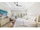 Bright main bedroom with a tray ceiling, a ceiling fan, white furnishings and access to the outdoor pool area at 20078 Elegante Ct, Venice, FL 34293