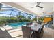 Covered patio with a pool, outdoor dining, lounge chairs, and view of lush landscaping at 20078 Elegante Ct, Venice, FL 34293