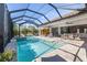 Screened-in pool area featuring a jacuzzi, outdoor seating, and an enclosed backyard at 20078 Elegante Ct, Venice, FL 34293