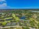 Expansive aerial view showcasing the golf course, tennis courts, lakes, and lush greenery of the community at 2081 Timucua Trl, Nokomis, FL 34275