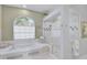 Bright bathroom with a soaking tub, a separate glass-enclosed shower, and a arched window at 2081 Timucua Trl, Nokomis, FL 34275