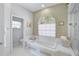 Bright bathroom featuring a soaking tub, a separate glass-enclosed shower, and a arched window at 2081 Timucua Trl, Nokomis, FL 34275