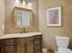 Elegant half bath with decorative mirror, stylish vanity, ornate artwork and neutral paint at 20909 Loggia Ct, Venice, FL 34293