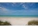 Beautiful view of a white sandy beach meeting the clear, turquoise ocean under a partly cloudy sky at 344 Monroe Dr, Sarasota, FL 34236