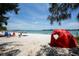 A sunny beach scene featuring people enjoying the water, with a red sun shelter in the foreground at 344 Monroe Dr, Sarasota, FL 34236