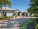 Charming white home featuring a brick driveway, well-manicured landscaping, and a pergola over the entryway at 355 W Royal Flamingo Dr, Sarasota, FL 34236