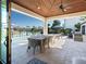 Covered patio with travertine tile, ceiling fan and an outdoor dining table with seating overlooking a canal at 355 W Royal Flamingo Dr, Sarasota, FL 34236