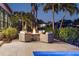 Cozy poolside firepit with comfortable seating surrounded by lush tropical foliage and palm trees at 355 W Royal Flamingo Dr, Sarasota, FL 34236