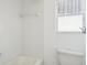 White tiled bathroom with a tub and window at 4119 Royal Palm Dr, Bradenton, FL 34210