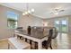 An inviting dining area with a dark wood table and seating bench beneath a modern chandelier and a ceiling fan at 4802 68Th Street E Cir, Bradenton, FL 34203