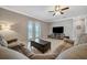 Living room featuring a large sofa, ceiling fan, a window overlooking the backyard, and a tv with console at 4802 68Th Street E Cir, Bradenton, FL 34203