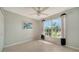 This bedroom features tile flooring, a ceiling fan, and a large window with black-and-white curtains at 4937 Thames Ln, Sarasota, FL 34238