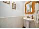 Stylish powder room featuring pedestal sink, decorative mirror, and neutral tile at 507 67Th W Ave, Bradenton, FL 34207