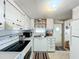 Well-lit kitchen featuring white cabinetry, a double basin sink, and modern appliances on a neutral floor tile at 511 50Th Avenue W Dr, Bradenton, FL 34207