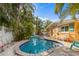 Outdoor pool with seating, white rock landscape, lush palms, and colorful home exterior at 5807 De Palmas Ave, Holmes Beach, FL 34217