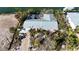 Aerial view of a waterfront home featuring a metal roof, tropical landscaping, and a screened-in porch at 607 Baronet Ln, Holmes Beach, FL 34217