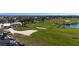 Wide angle shot showing the golf course, with manicured greens, a clubhouse, and parking, all near a waterfront community at 607 Baronet Ln, Holmes Beach, FL 34217