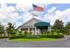 Front exterior of the clubhouse with an American flag, palm trees and manicured landscaping at 6330 Green Oak Cir # D, Bradenton, FL 34203