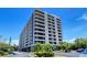 Multi-story condo building shows tropical landscaping and a parking area on a clear, sunny day at 6415 Midnight Pass Rd # 508, Sarasota, FL 34242