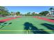 Outdoor tennis courts featuring green playing surfaces, red borders, surrounding greenery, and overhead lighting at 6415 Midnight Pass Rd # 508, Sarasota, FL 34242