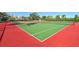 Brightly colored red and green tennis courts in a sunny outdoor setting, lined with green trees and foliage at 6415 Midnight Pass Rd # 508, Sarasota, FL 34242