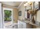 Bathroom with door opening to lush tropical landscape, granite counters, and white vanity at 6606 Holmes Blvd # 3, Holmes Beach, FL 34217