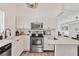 Modern kitchen with stainless steel appliances, white cabinetry, and laminate flooring at 6624 Fairway Dr, Sarasota, FL 34243