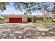 Charming single-story home featuring a red garage door, brick driveway, and lush landscaping at 6640 Peacock Rd, Sarasota, FL 34242