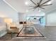 Bright living room with gray wood floors, modern ceiling fan, neutral furnishings, and a view of the kitchen at 7225 Las Casas Dr, Sarasota, FL 34243