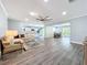 Spacious living room with gray wood floors, ceiling fan, open floorplan, and a glimpse of the white kitchen at 7225 Las Casas Dr, Sarasota, FL 34243