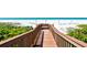 Wooden boardwalk leading to a serene beach with lounge chairs and umbrellas at 775 Longboat Club Rd # 406, Longboat Key, FL 34228