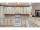 Bright kitchen featuring white cabinets, light countertops, and decorative backsplash at 8414 Wethersfield Run # 102, Lakewood Ranch, FL 34202