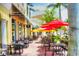 Inviting outdoor dining area with tables, chairs, umbrellas, and colorful buildings in the background at 8414 Wethersfield Run # 102, Lakewood Ranch, FL 34202