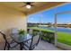 A screened lanai with patio table and seating area overlooks a pond and golf course at 8414 Wethersfield Run # 102, Lakewood Ranch, FL 34202