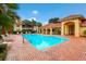 A community swimming pool with a brick deck, lounge chairs and tropical landscaping at 8414 Wethersfield Run # 102, Lakewood Ranch, FL 34202