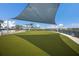 Manicured community lawn with shade structure overlooks neighborhood homes, lush landscaping, and a community lake at 10470 Spring Tide Way, Parrish, FL 34219