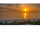 Golden sunrise view of a beach with palm trees and lounge chairs near the ocean at 1211 Gulf Of Mexico Dr # 701, Longboat Key, FL 34228
