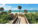 Picturesque view from a wooden boardwalk leading to a pristine sandy beach with palm trees and blue skies at 1211 Gulf Of Mexico Dr # 701, Longboat Key, FL 34228