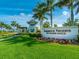 Hammock Preserve entrance with lush landscaping, flowers, and palm trees under a bright blue sky at 12325 Marsh Pointe Rd, Sarasota, FL 34238