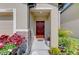 Covered front entrance with lush landscaping and a bright red door adding charm and curb appeal at 13528 Sunset Sapphire Ct, Parrish, FL 34219