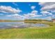 Picturesque view of a calm pond reflecting the sky, bordered by vibrant green grass at 13528 Sunset Sapphire Ct, Parrish, FL 34219