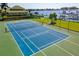 View of blue and green tennis courts with a waterway and boat dock in the background at 1522 3Rd Street E Cir, Palmetto, FL 34221