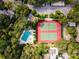 Aerial view showcasing a pool and tennis courts amidst lush trees, highlighting recreational amenities at 1680 Brookhouse Cir # 110, Sarasota, FL 34231