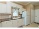 Bright kitchen featuring white cabinets, light countertops, a double sink, and a modern white refrigerator at 2002 Palm View Rd, Sarasota, FL 34240